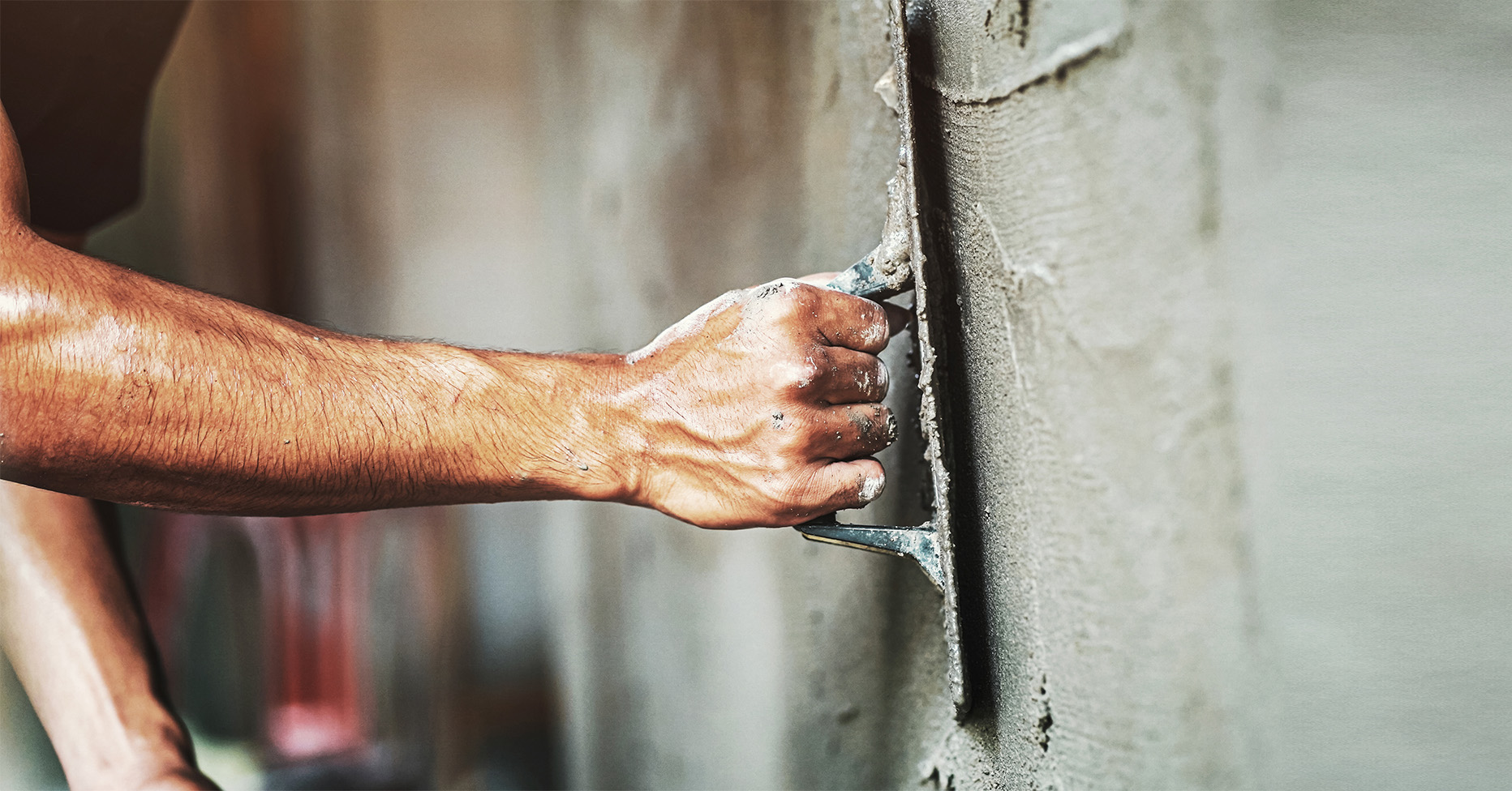 Hand mit Spachtel an Wand